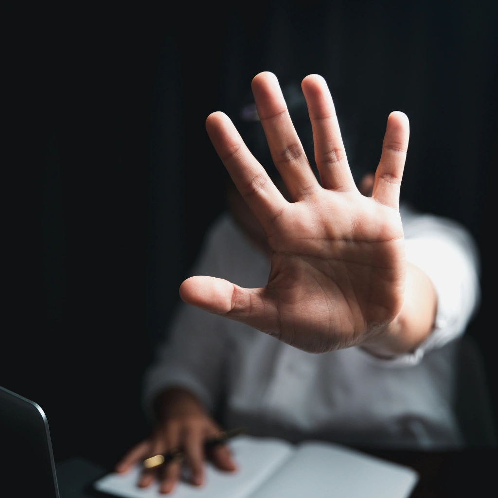 Employee showing stop gesture to prevent workplace harassment in French supervisor training