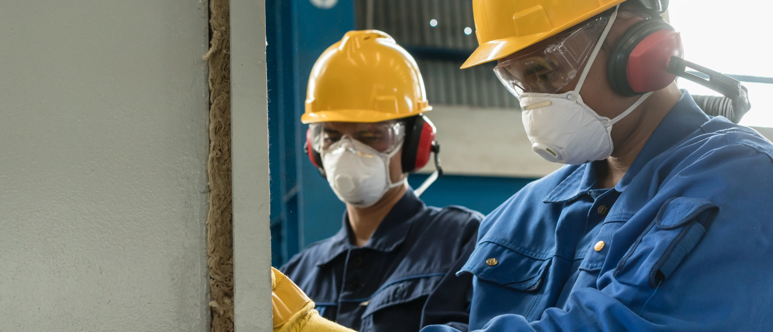 Worker reviewing WHMIS labels on chemical containers with PPE gloves and goggles.