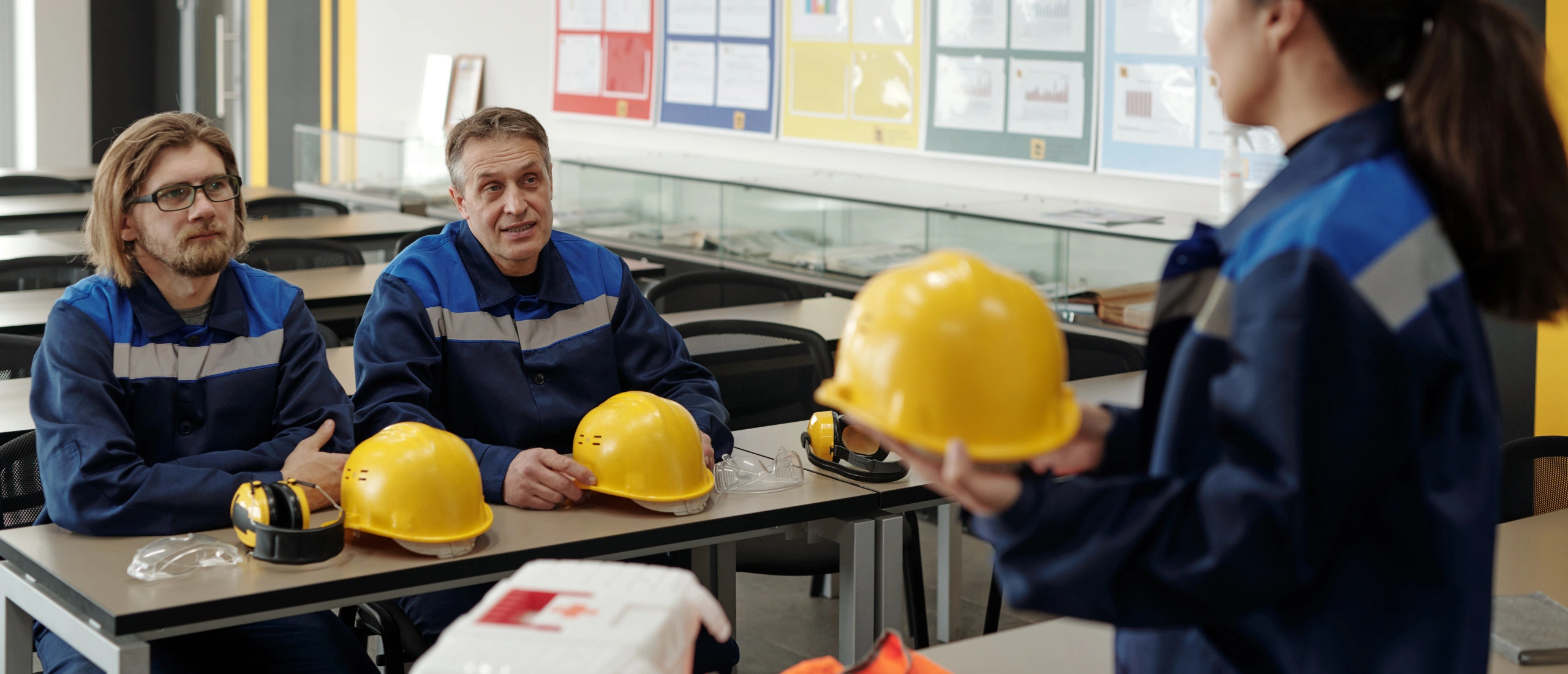Safety professionals and workers evaluating hazards and implementing OHSMS procedures in an industrial environment.